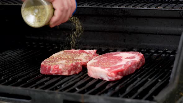 Putting spices two rib-eye steaks on in slow motion.