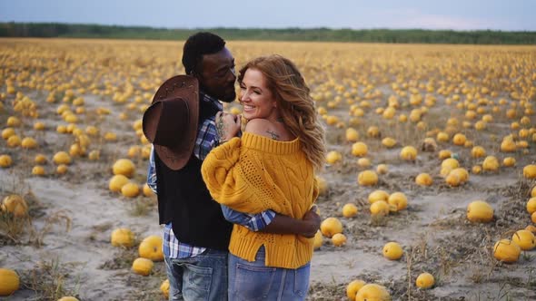 Couple Stands in Pumpkin Field and Hugs Rear View