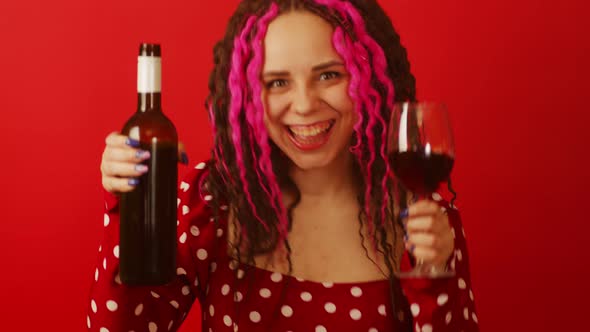 Young Beautiful Woman with Glass of Wine and Bottle on Red Background