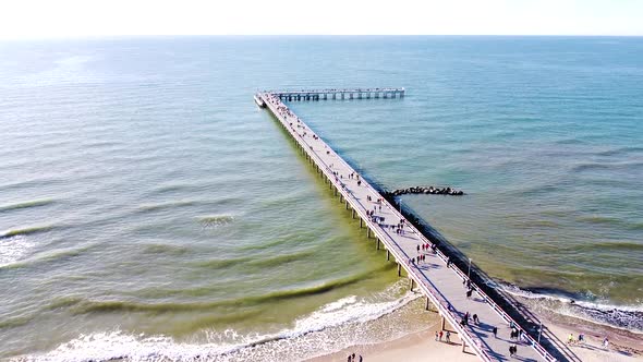 Aerial static view of Palanga bridge with people and calm Baltic sea