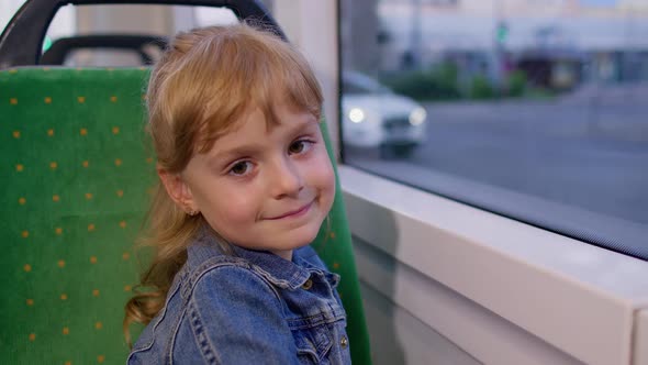 Cheerful Cute Child Girl Passenger Riding at Public Modern Bus or Tram Transport Looking Out Window