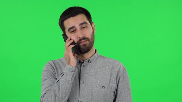 Portrait of Brunette Guy Is Angrily Talking for Mobile Phone. Green Screen