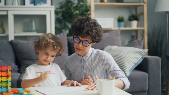 Smiling Child Is Drawing with Pencils While Loving Mother Is Talking Helping