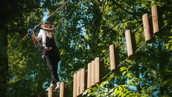 Woman Crossing a Construction of the Rope and Stumps - an Entertainment Attraction in the Green