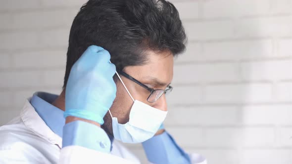 Side View of a Young Doctor Putting Surgical Face Mask Indoor