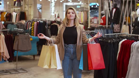 Girl Meditates with Packages in Her Hands in a Store