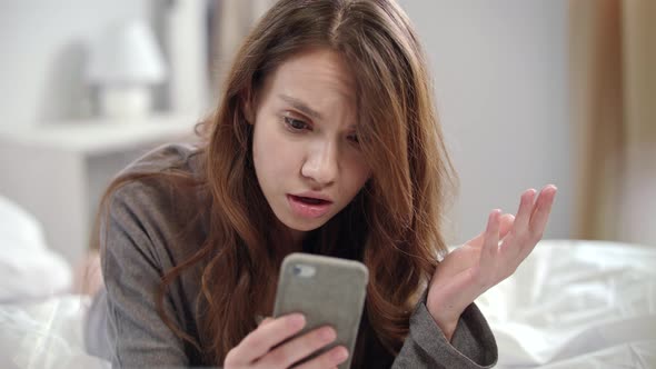 Shocked Woman Watching Video News Online on Mobile Phone at Morning