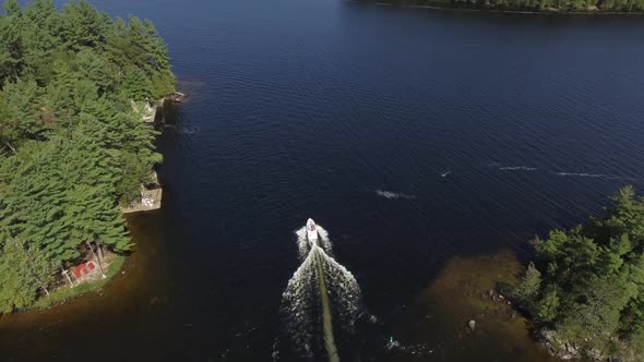 aerial family boat passes through shallow channel cottage country tilt up reveal 4k