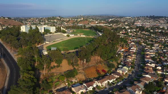 Flying over Beautiful Surburban Los Angeles Town Towards Epic High School with Green Football Field