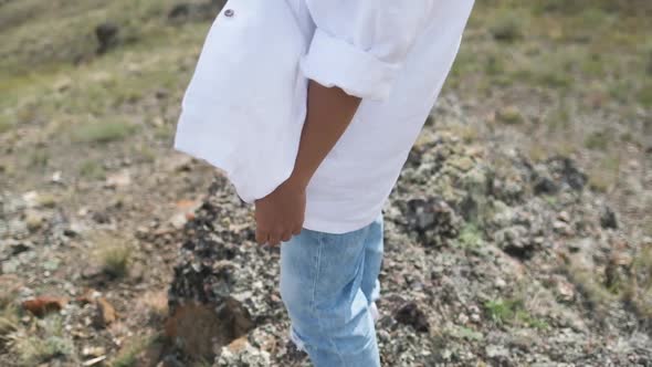 Close-up White Shirt Fluttering in the Wind. Hat and Shirt Close-up on a Background of Mountains.