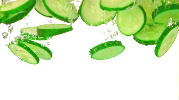 Super Slow Motion Chopped Cucumbers Fall Under the Water with Air Bubbles