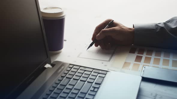 Composition From a Laptop with a Glass of Coffee and a Person's Hand Making a Note on the Drawing