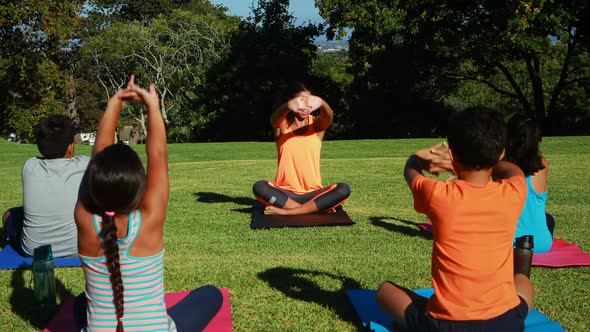 Yoga instructor instructing children in performing exercise