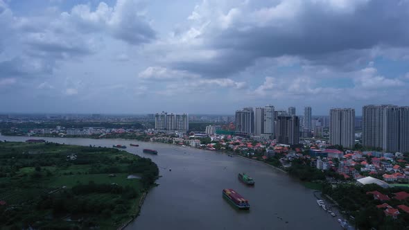 Aerial panning shot of Large river boats carrying shipping containers on the Saigon River in Ho Chi