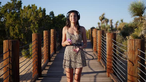 A beautiful young woman listening to music streaming from her smartphone on her headphones while wal