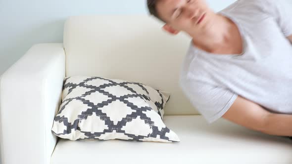 Tired Young Man Falls Down on Couch with Pillow in Room