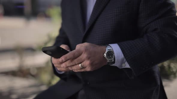 Close up of an texting on mobile phone outside with blurred background