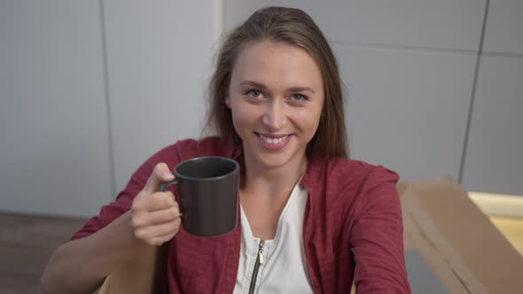 Front View Portrait Smiling Slim Beautiful Young Woman Toasting Cup Looking at Camera Sitting in