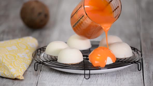 Close up confectioner decorating cakes with mirrored glaze at kitchen.