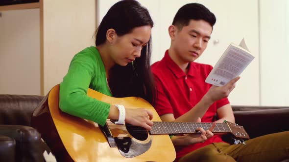 Couple playing guitar in living room