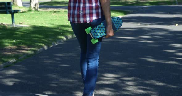 Woman with Skateboard Walking on Street Near Park 4k