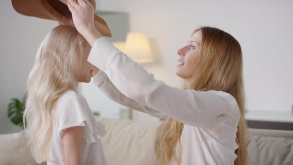 Happy Mother Putting Hat on Cute Daughter