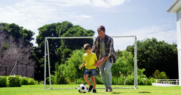 Father assisting son to play football