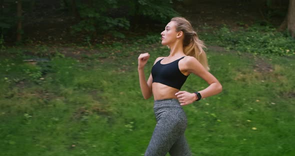 Young Blonde Woman Jogging in Park, Side View