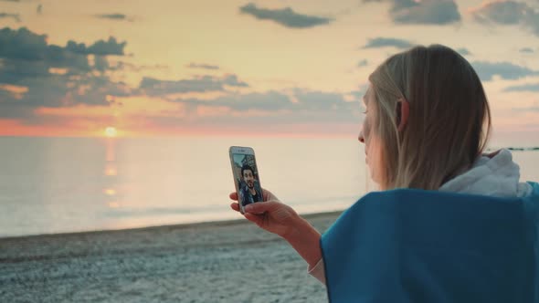 Young Woman Making Video Call to Her Friend with Smartphone on the Beach