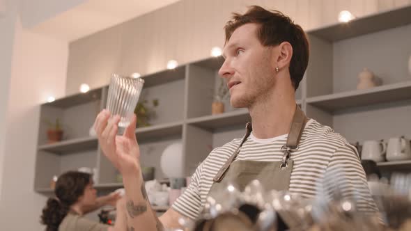 Male Barista Wiping Glasses behind Counter