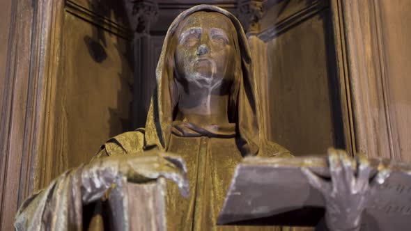 Statue of a hooded figure with a book,raised arm,alcove,at night,Prague,Czechia.