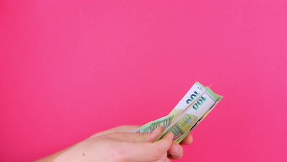 Hand in holds EURO money bills on pink color background. Counting cash european 100 banknote Casino