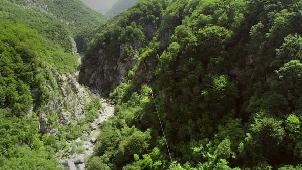 Aerial view of couple canopying over the forest in zip-line at Slovenia.