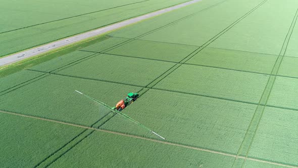 The Protection Of Plants.Tractor Spraying A Green Wheat Field