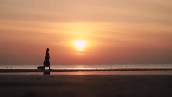 Woman and Corgi Dog Walk Along Sea Beach Under Sunset Sky During Vacation Spbi