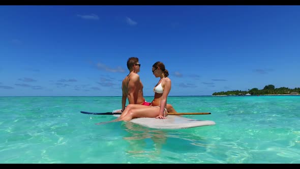 Family of two engaged on exotic sea view beach vacation by blue water with white sandy background of