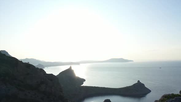 Aerial Silhouette of Young Woman Standing on the Top of a Mountain Over the Sea at Sunrise. Side