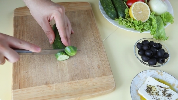 Hand Cutting Cucumber On Cutting Board With Sharp