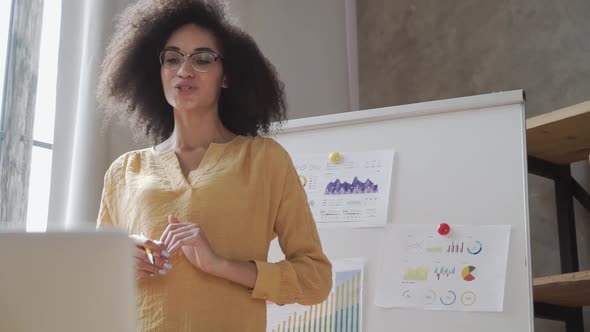 African American Female Holds a Conference with Paperwork Documents and Reports By Video Call From