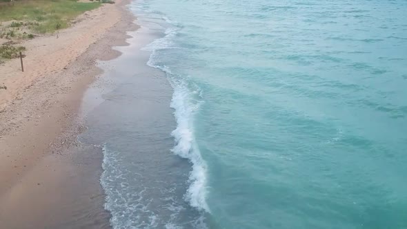 Aerial tilt up view of ocean blue waves break on a beach. Sea waves and beautiful sand beach aerial