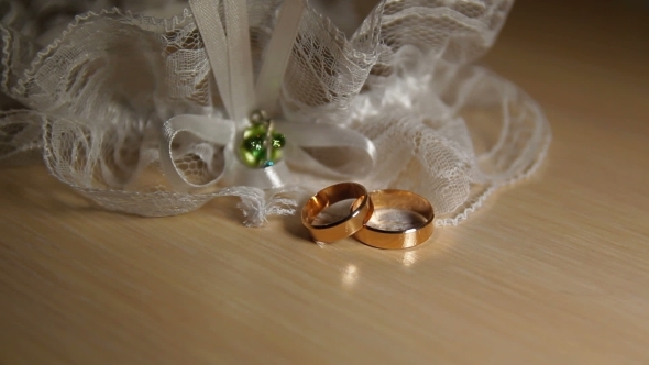 Two Wedding Rings With Lace On The Table