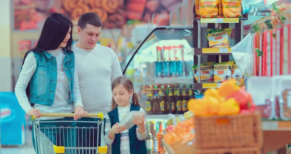 Mother Father and Children Picking Out Fruit in a Package in Supermarket