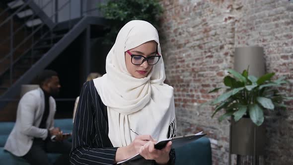 Businesswoman in Hijab Signing the Documents and Looking at Camera with Cute Smile