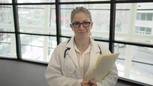 A Blonde Caucasian Female Medical Professional Walks Up To The Camera (3 Of 4) alt