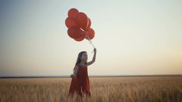 Happy Young Girl with Balloons Running in the Wheat Field at Sunset  Video.