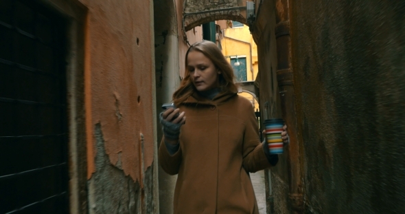 Woman With Phone And Coffee Walking In Venice alt