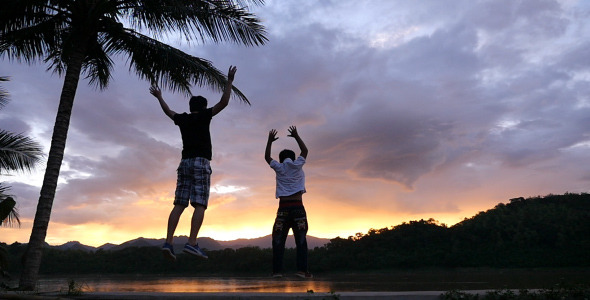 Father And His Son Jumping In Sunset