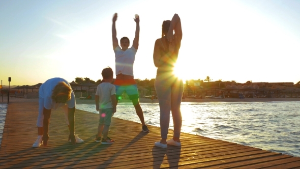 Family Exercising On The Pier At Sunset