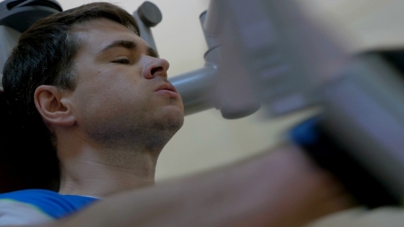 Young Man Doing Exercise On Chest Press Machine alt