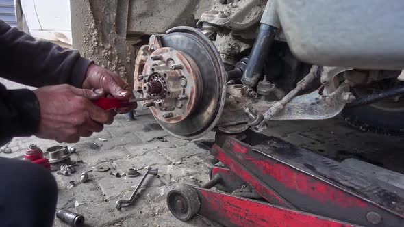 Car Mechanic Replaces Car Wheel Ball With Torx Screwdriver In Repair Shop